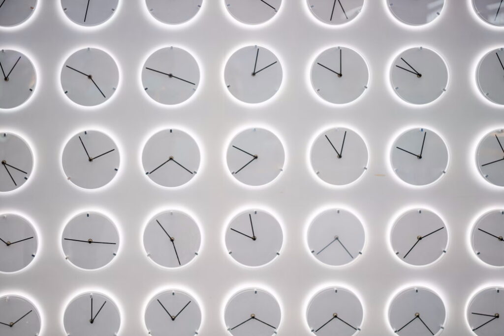 A white wall with multiple blank white clocks on it all showing a different time.