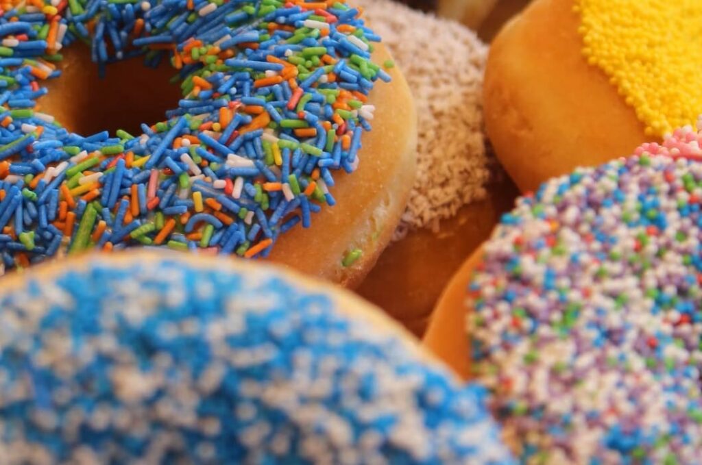 close up of a pile of ring doughnuts with blue sprinkles on top