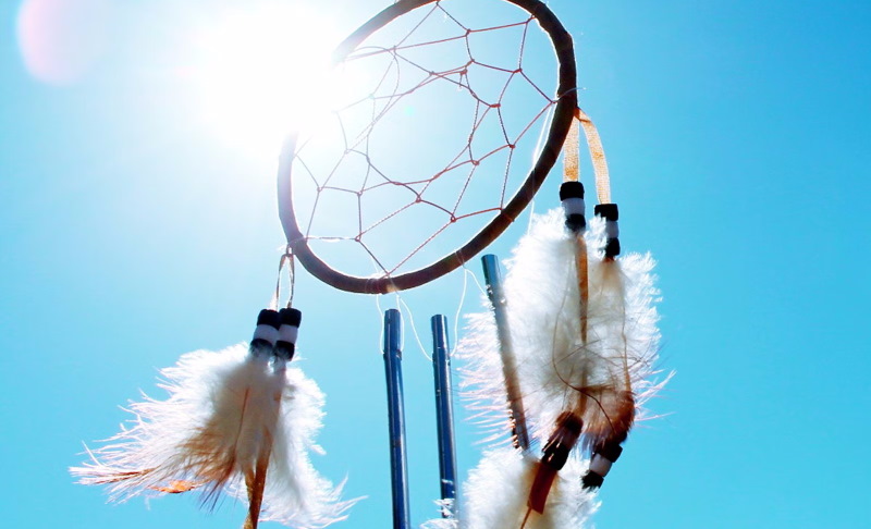Dream catcher against sunny background with blue sky