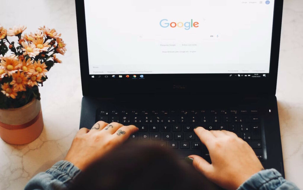 Hands typing on laptop displaying the Google search box