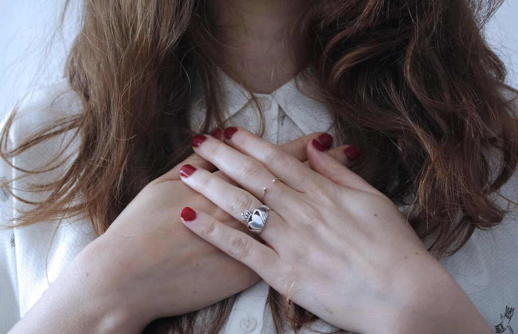 Person wearing white shirt holding their hands over their chest