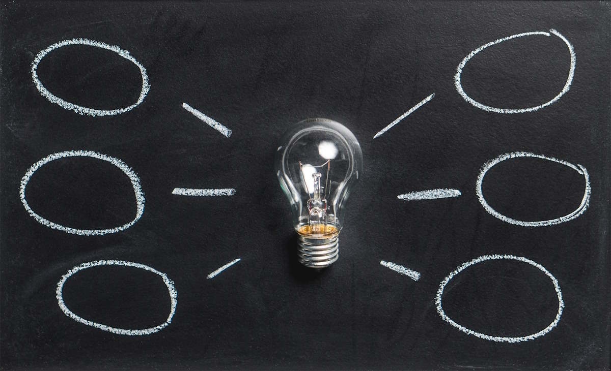 A lightbulb lying on a chalkboard, with lines drawn leading away from the bulb to several bubbles
