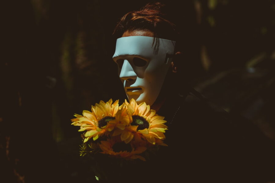 Man wearing a white mask holding a bunch of flowers