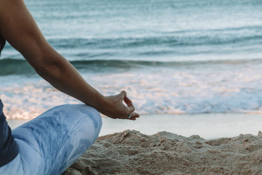 An out of shot person sat on the beach meditating