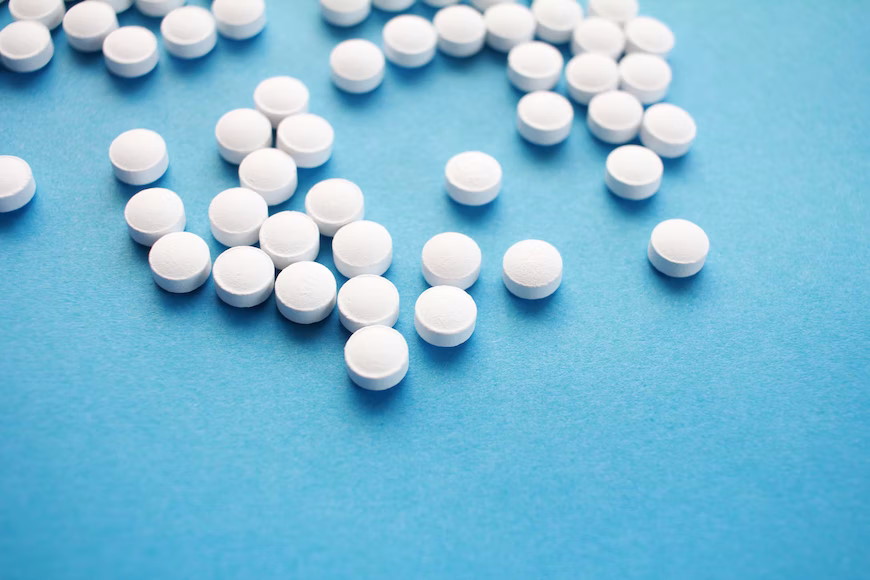 Pile of white pills on a blue surface