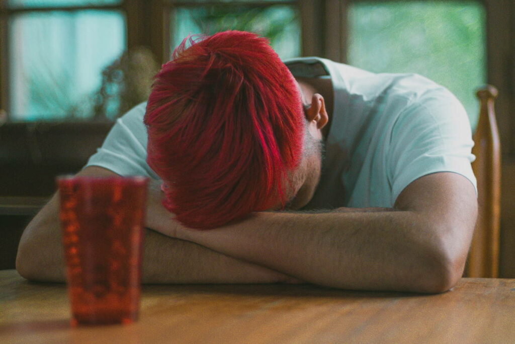 Man with red hair resting his head on his arms
