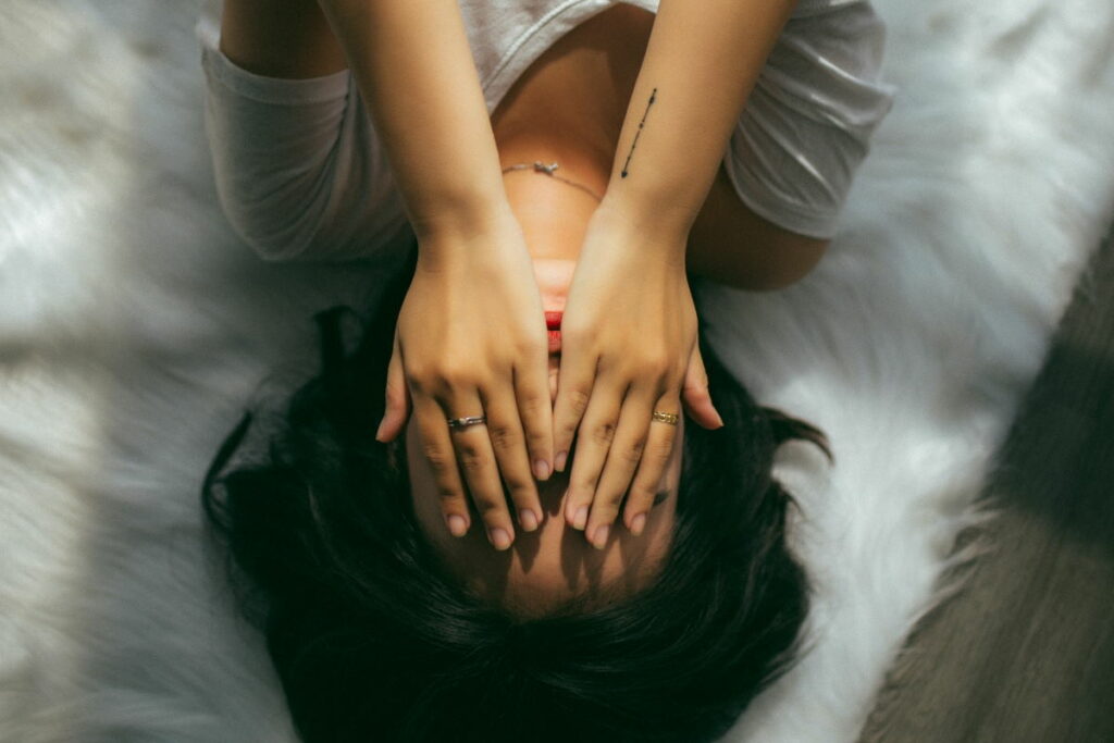Woman lying upside down with her hands over her face