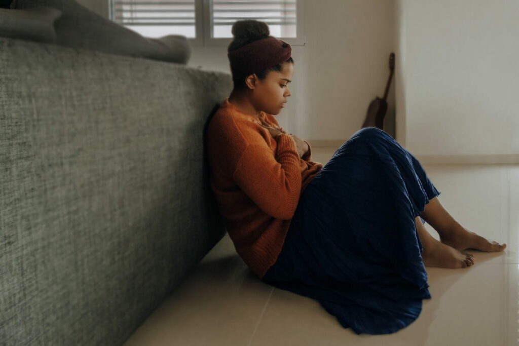 Woman in an orange jumper sat on the floor