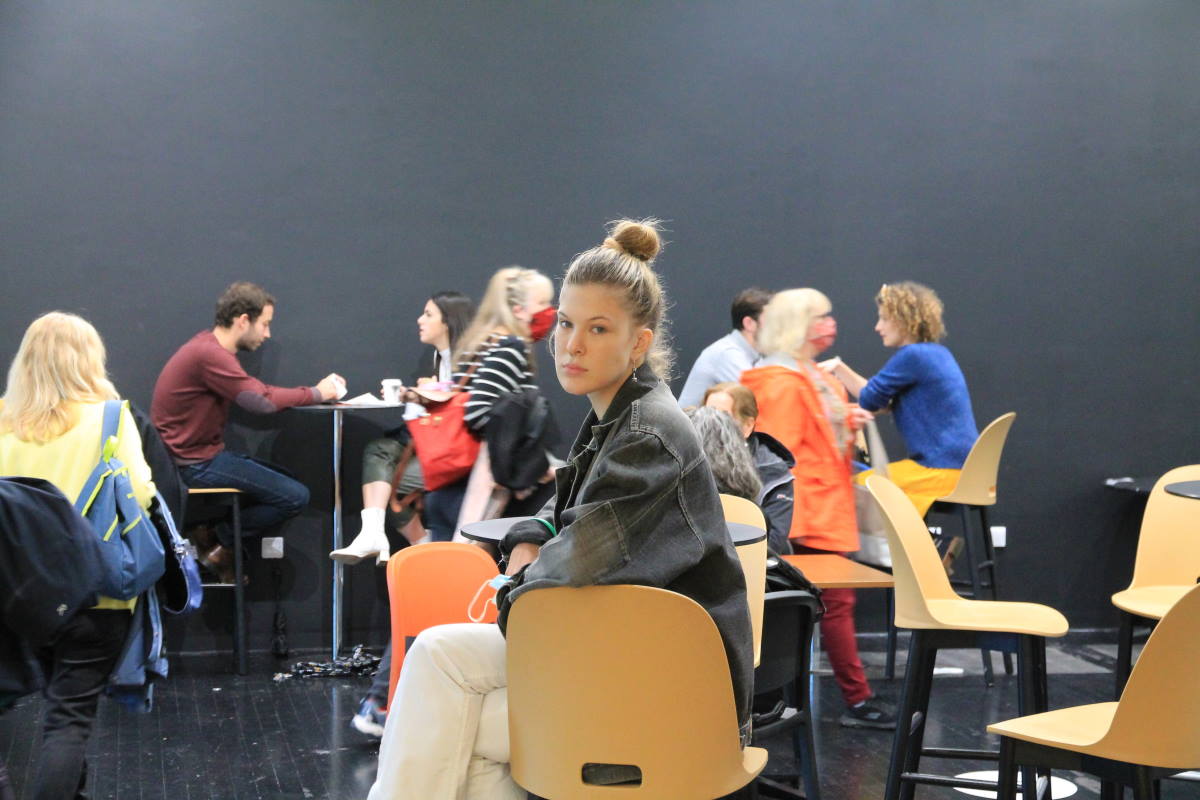 Woman sat sideways on a chair with people in the background