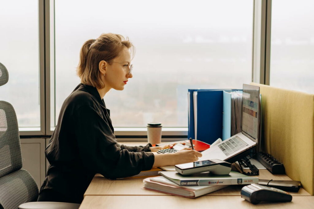 Woman wearing glasses using a laptop whilst sitting at a desk