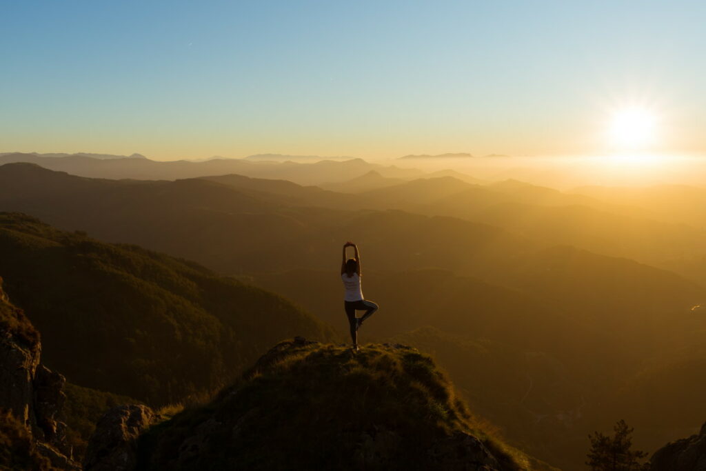 Woman doing yoga on a hill during sunrise